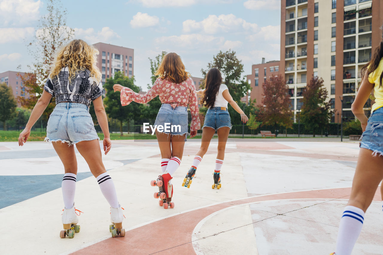 Friends roller skating and dancing together at sports court