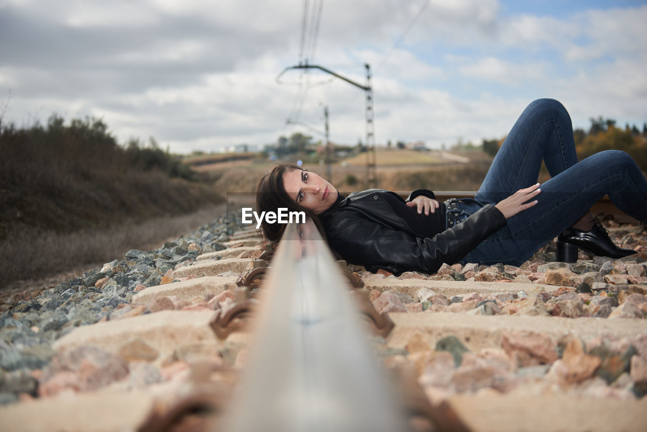 Low section of woman sitting on railroad track