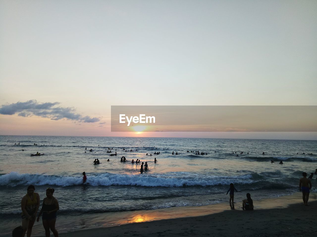 PANORAMIC VIEW OF PEOPLE ON BEACH AGAINST SKY DURING SUNSET