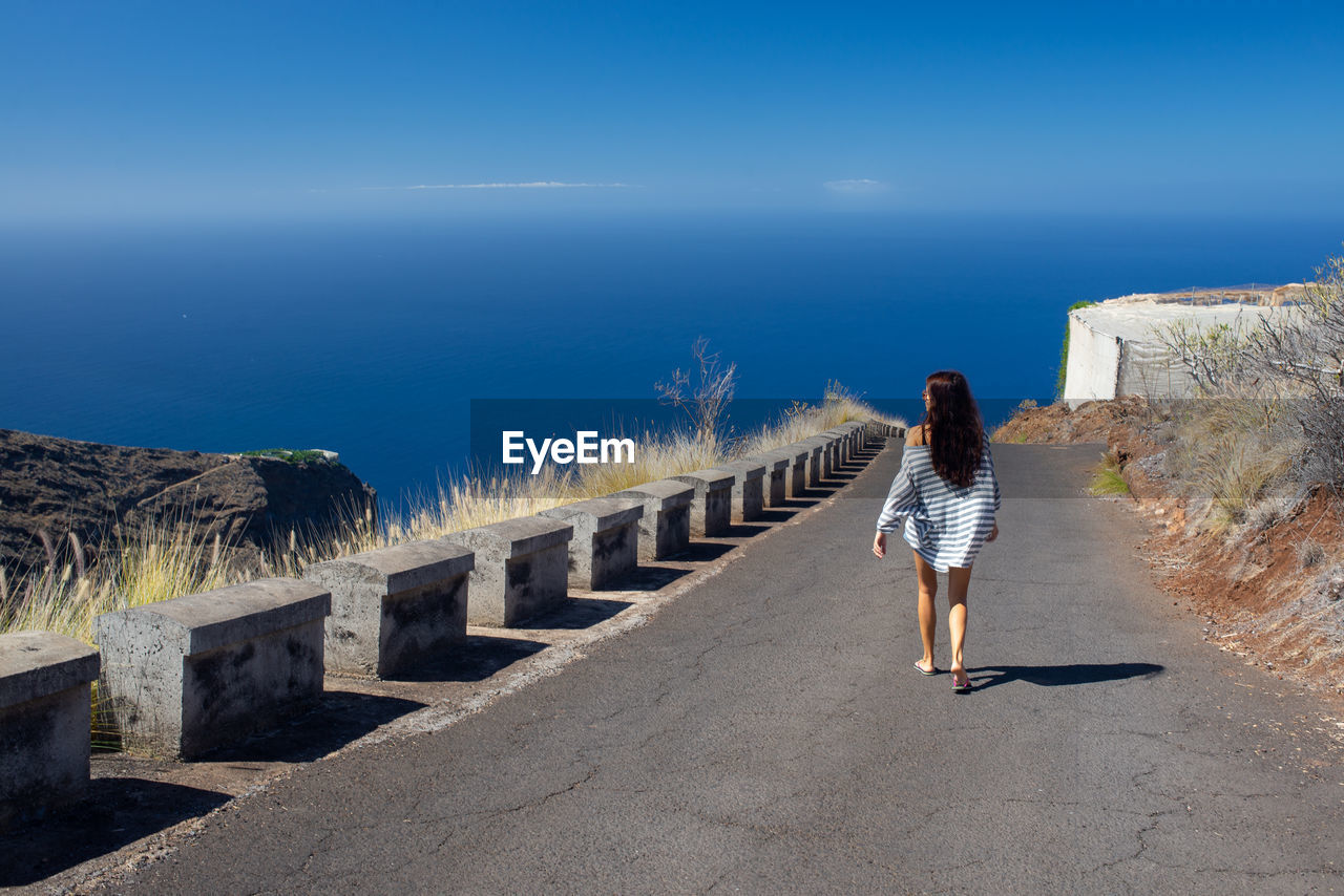 Rear view of woman walking on road