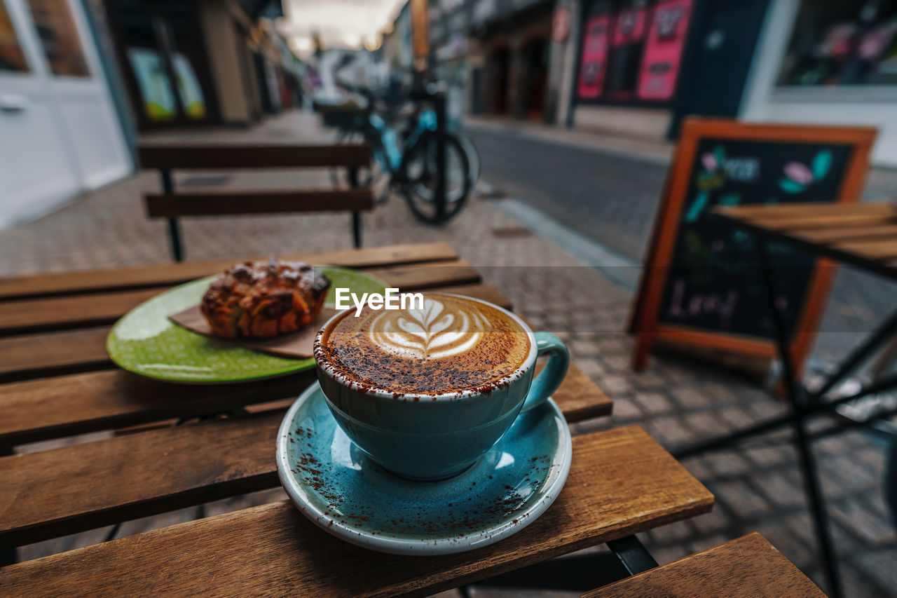 Cup of cappucino shot in front of a paved raod in the center of carlow, ireland on an early morning.