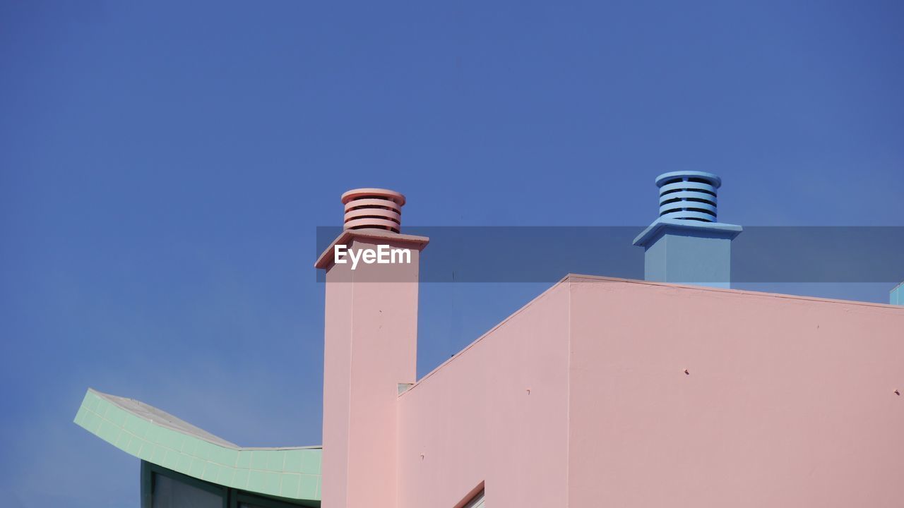 Low angle view of pastell colored part of building against clear blue sky