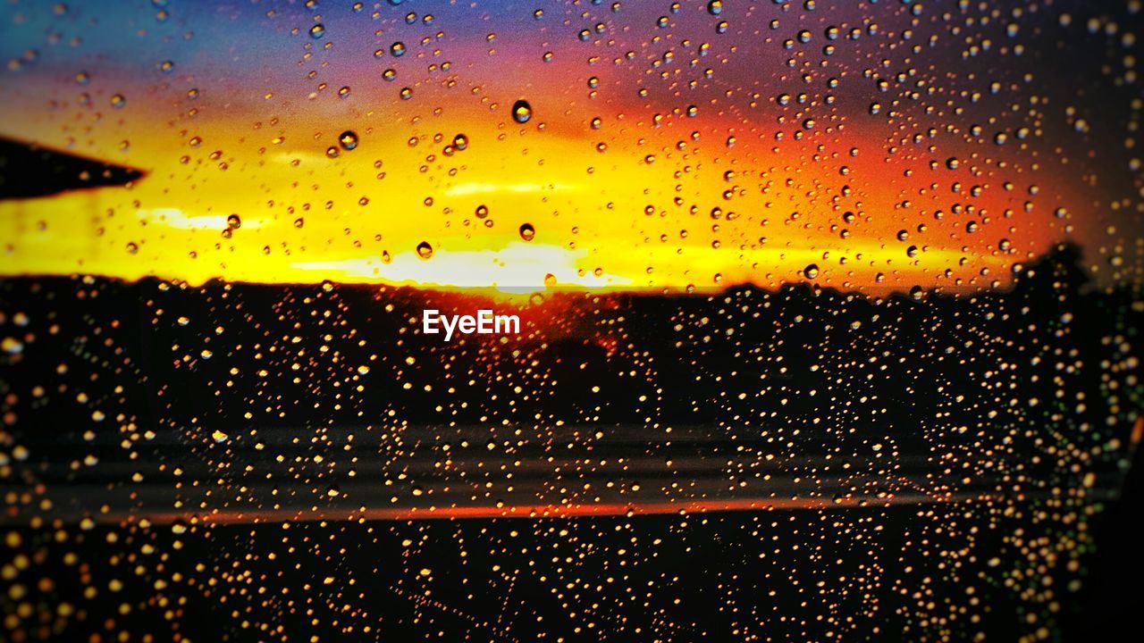 Orange sky seen through wet glass window during monsoon