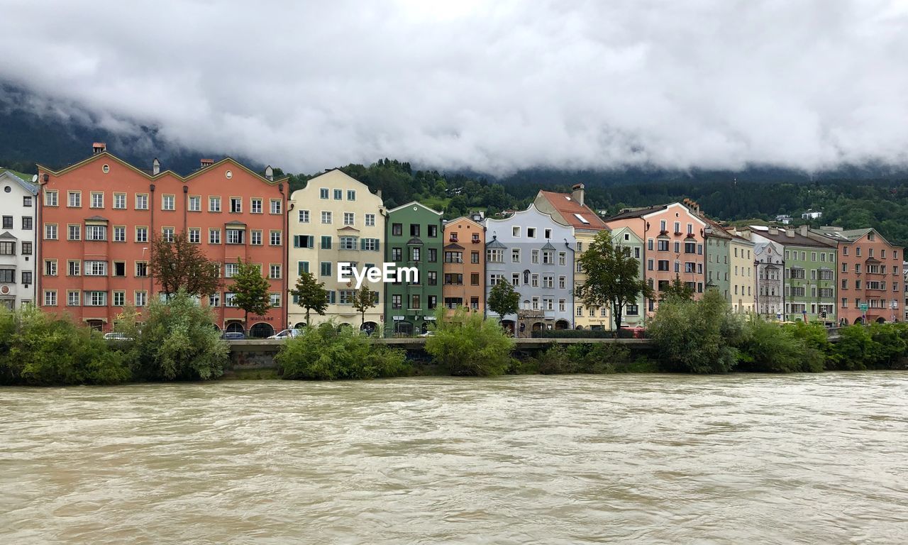 Buildings by river against sky in city