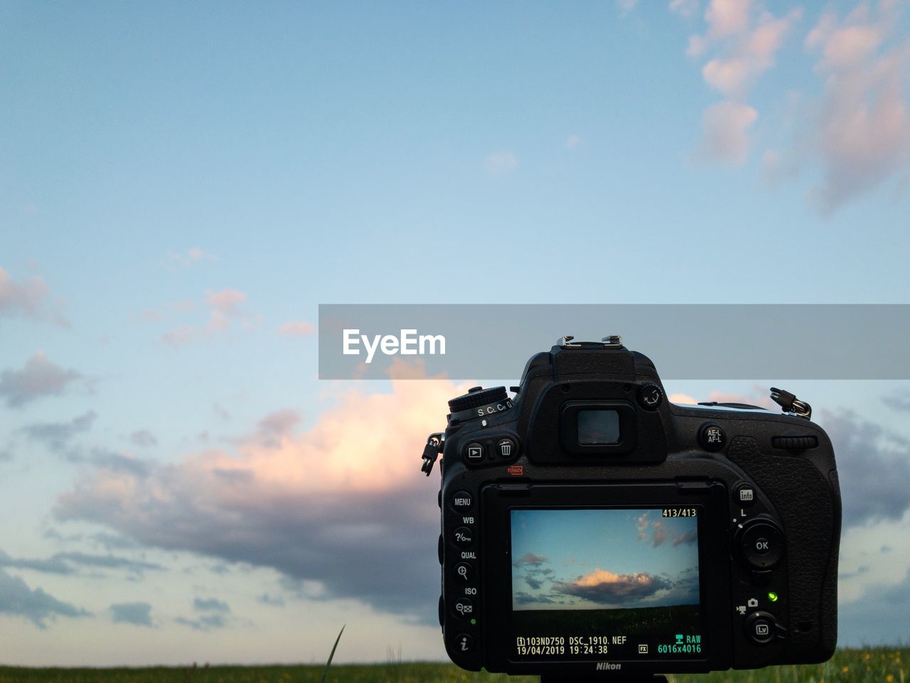 CLOSE-UP OF CAMERA ON PHOTOGRAPHING AGAINST SKY