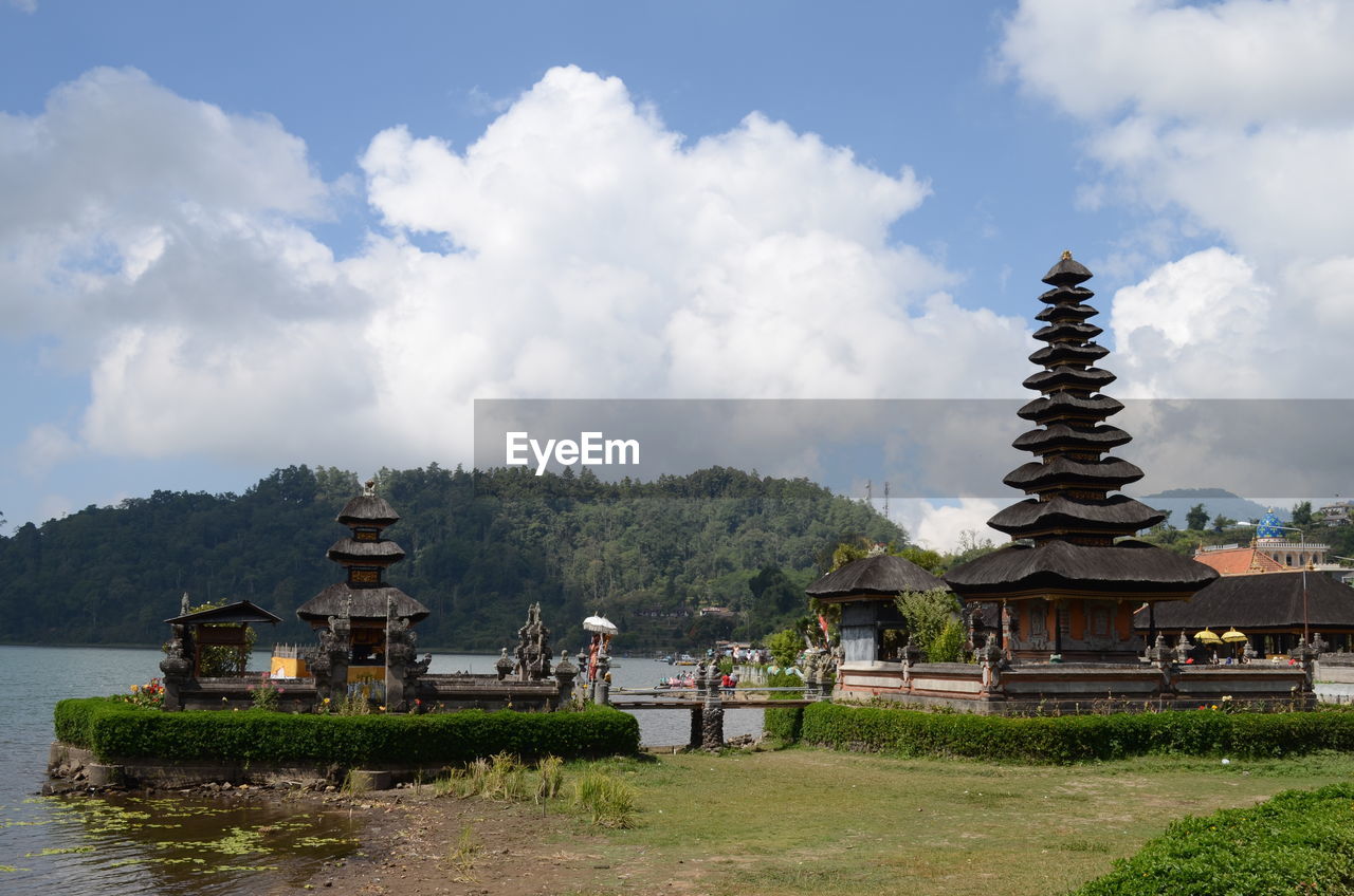 Temple building by lake against sky