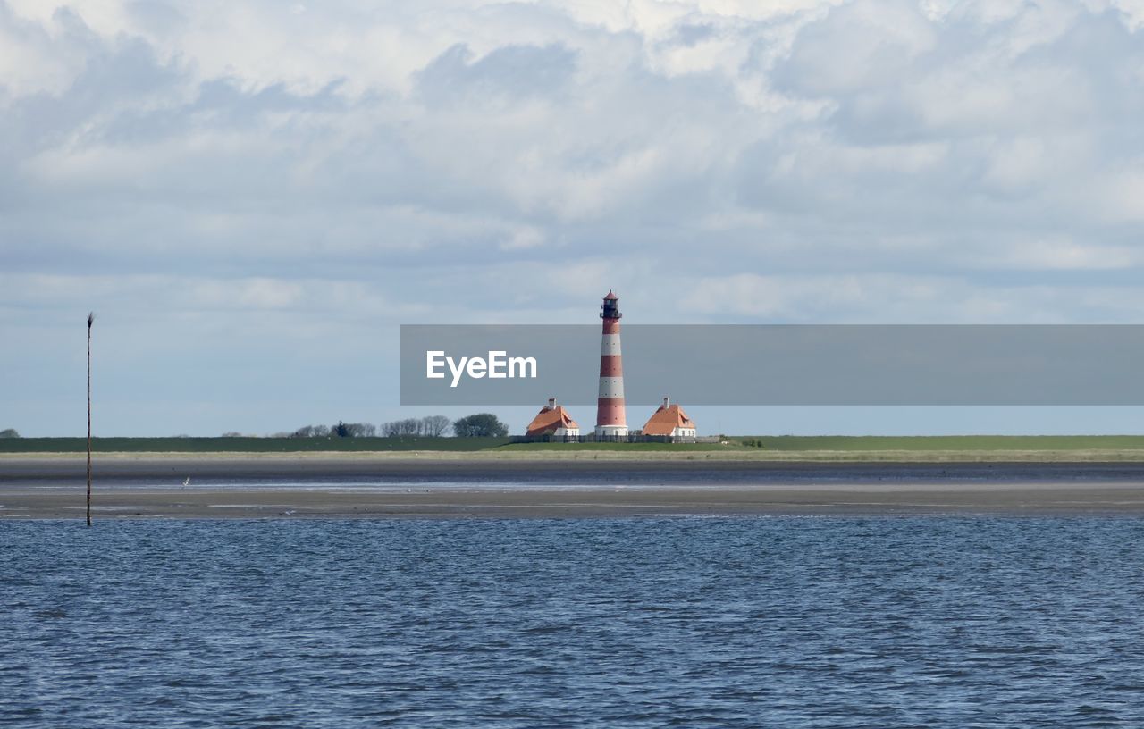 Lighthouse by sea against sky