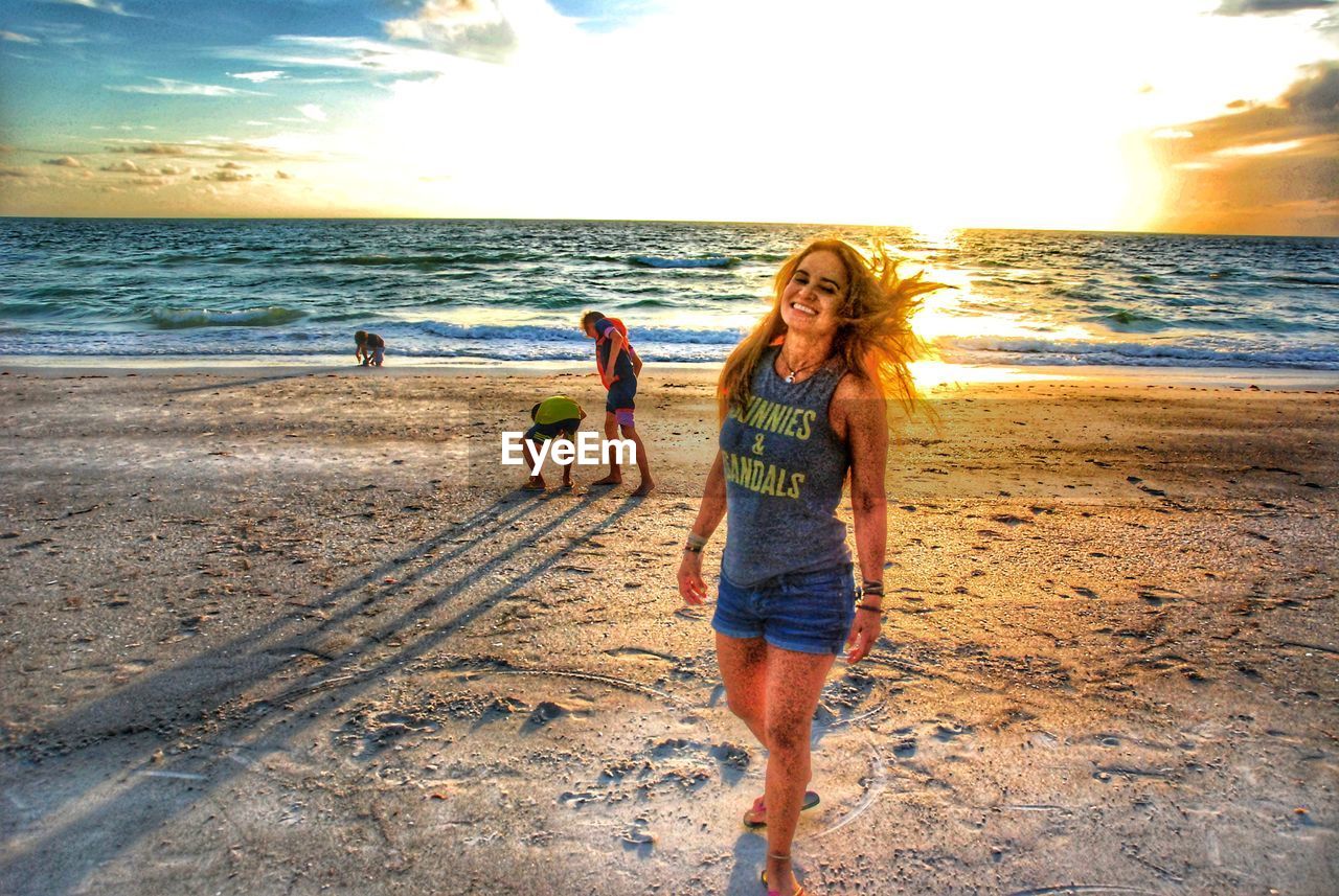 YOUNG WOMAN ON BEACH AGAINST SEA AGAINST SKY