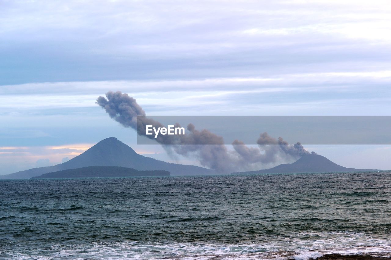 Smoke emitting from volcanic mountain against sky