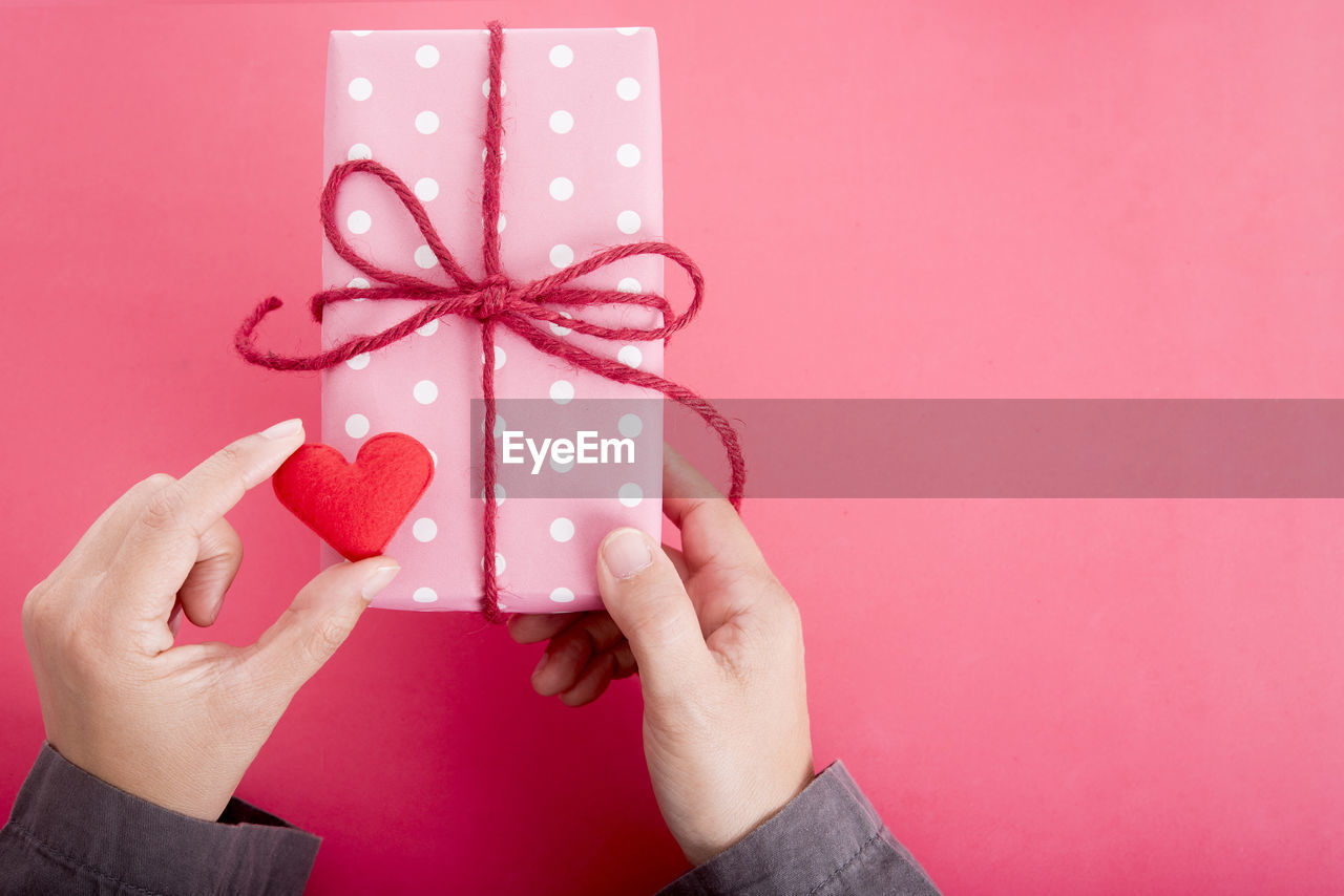 Cropped hands of woman holding gift on table