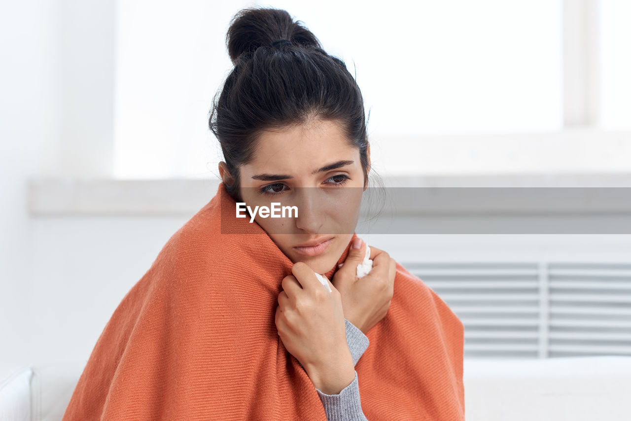 Ill woman looking away while sitting at home