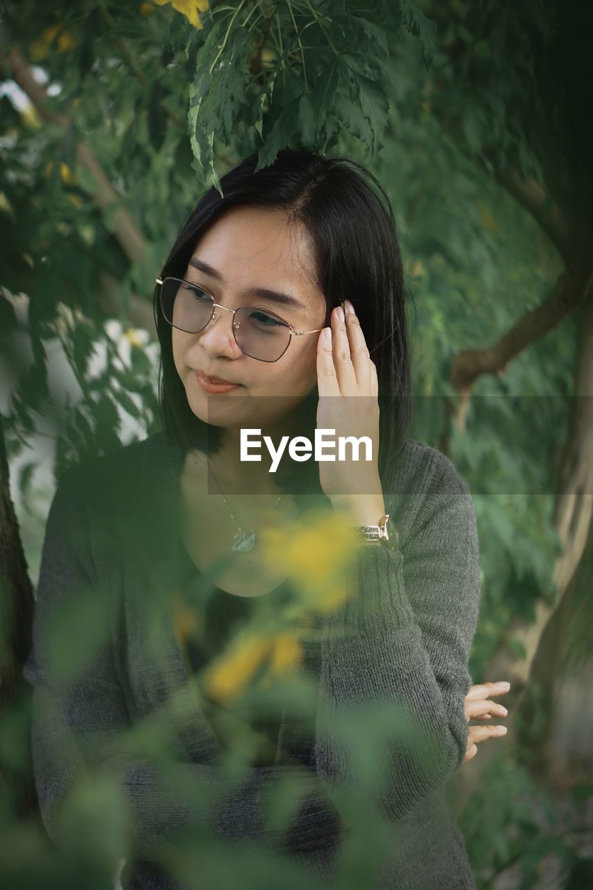 Portrait of young woman standing against plants