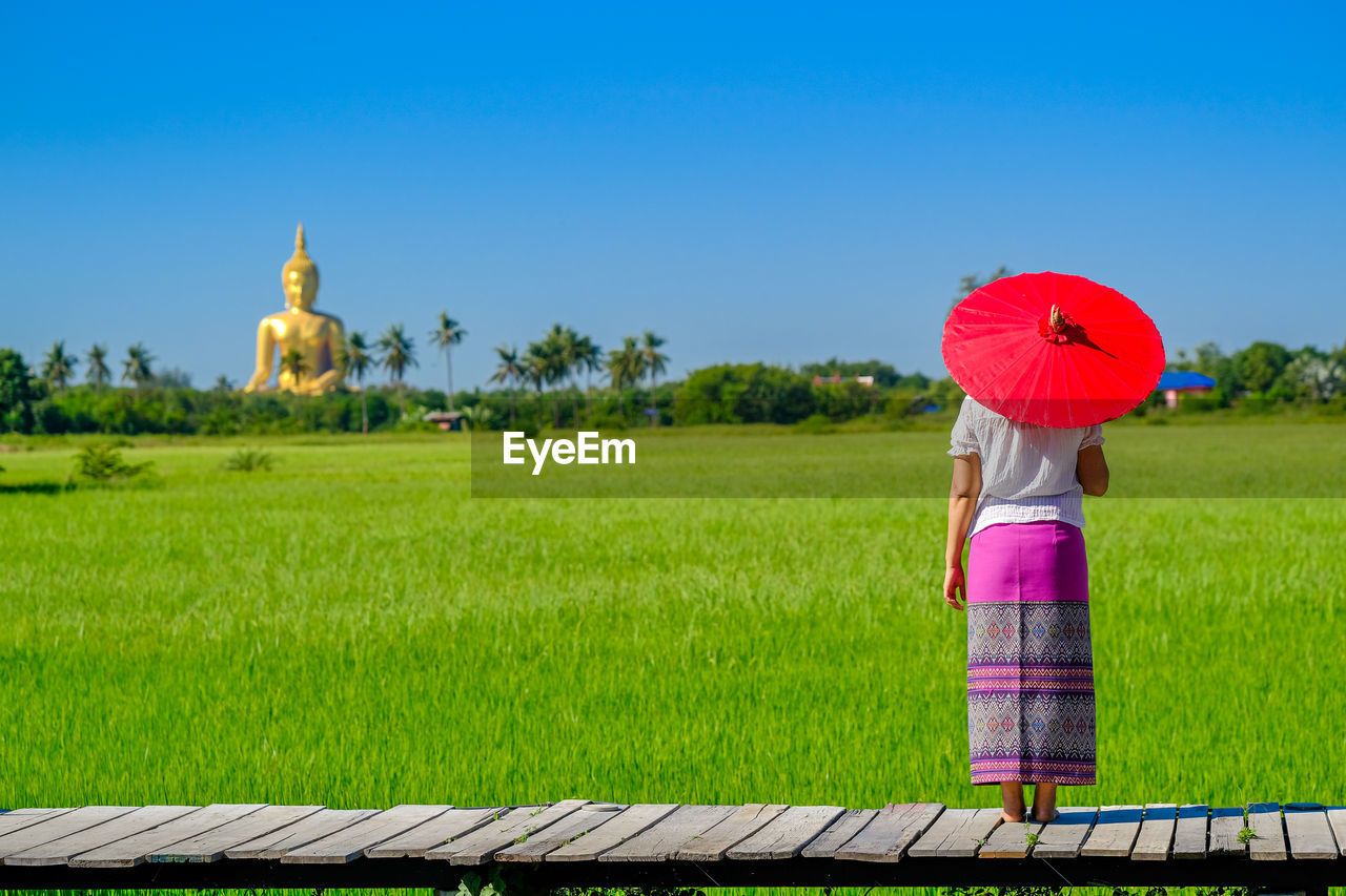 Woman standing on grass against sky