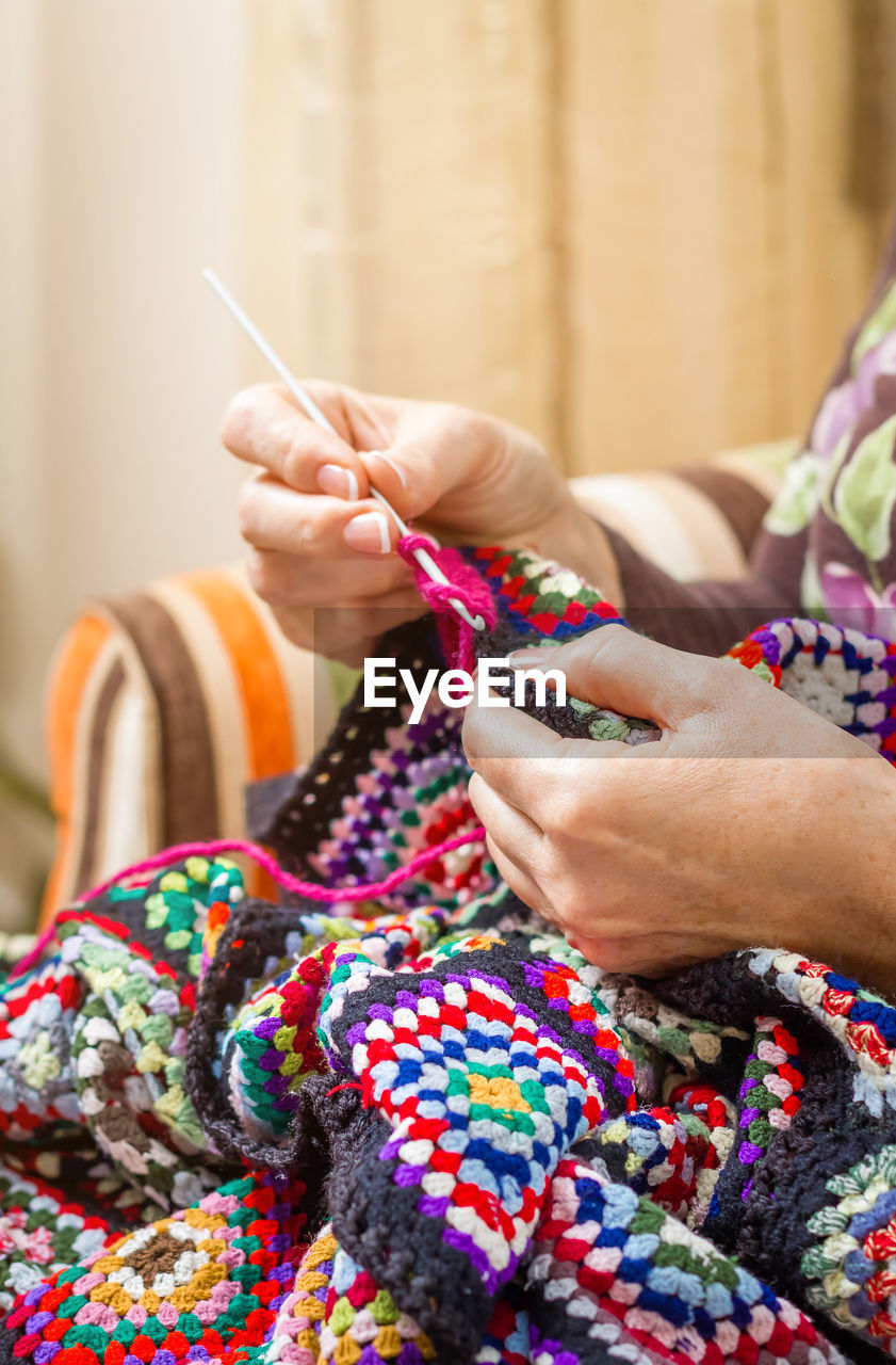 Hands of woman knitting a vintage wool quilt