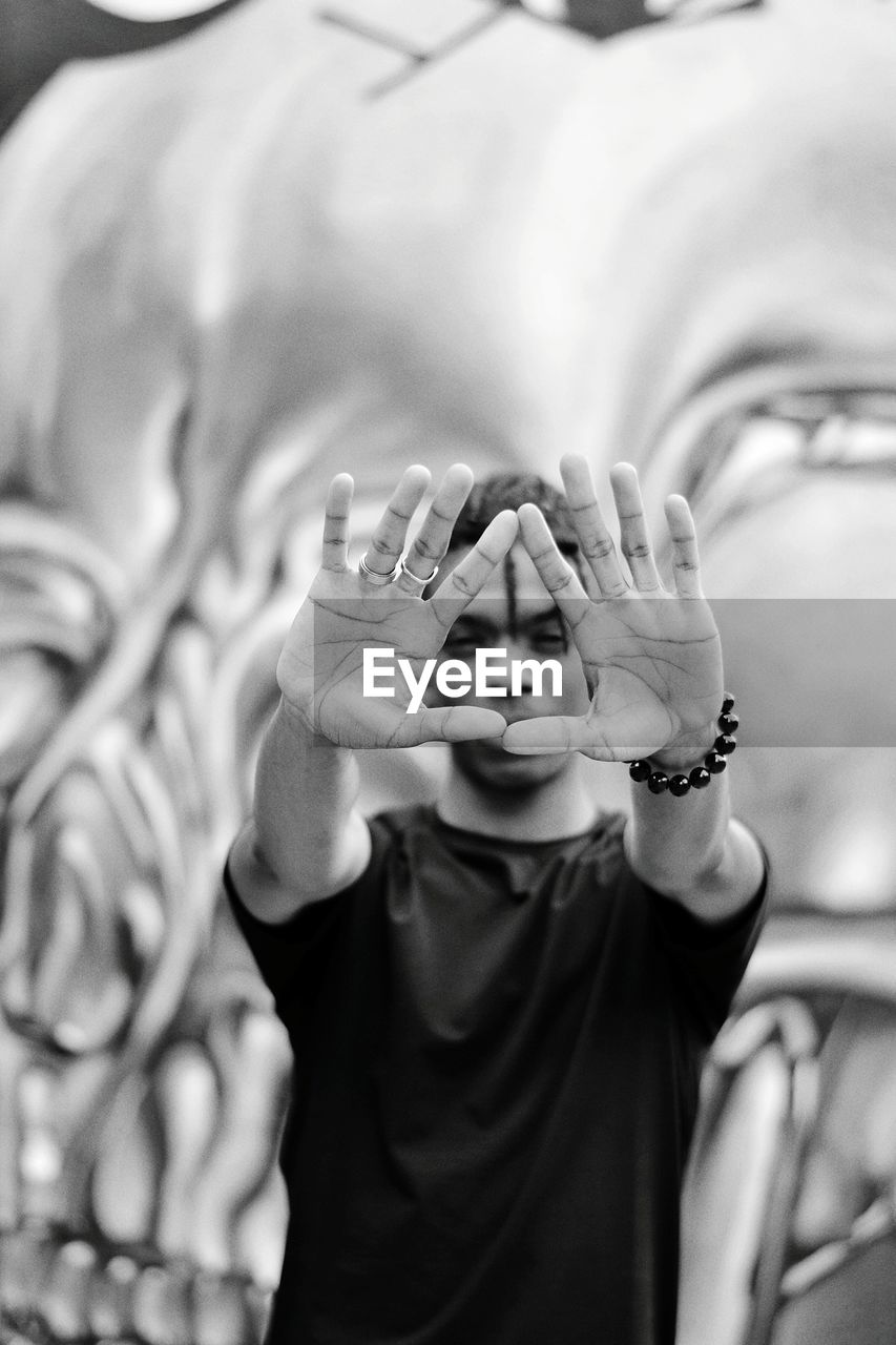 Portrait of young man gesturing against mural on wall