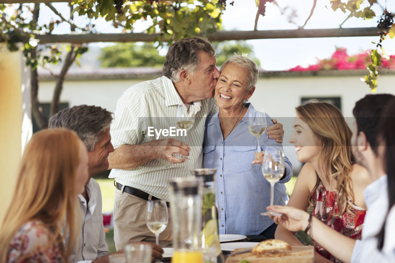 Happy senior couple with family having lunch together outside