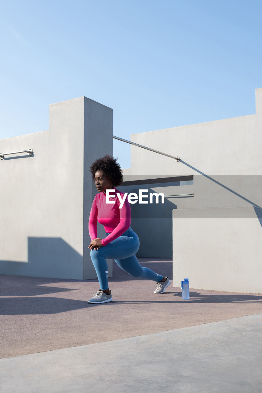 Black sportswoman stretching during training