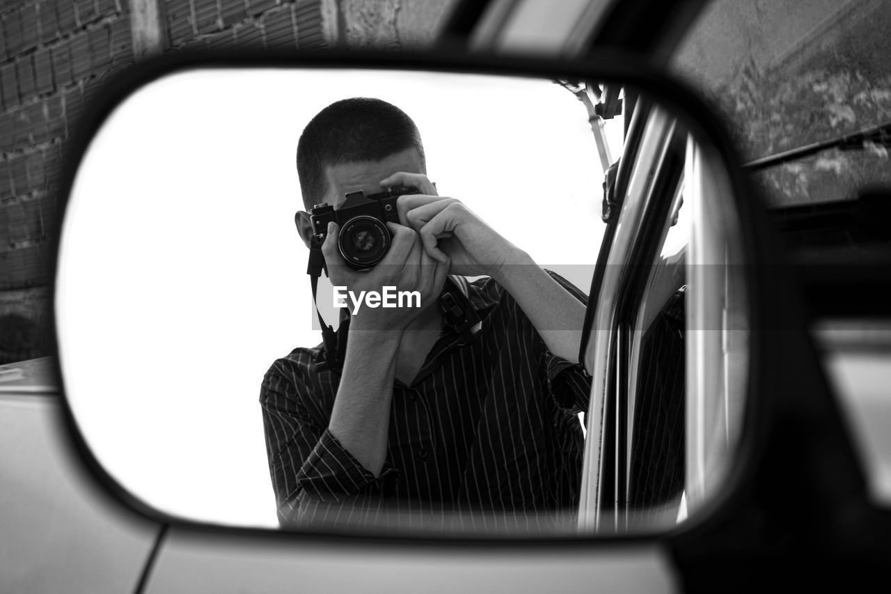 Young man takes a photo with an old camera.