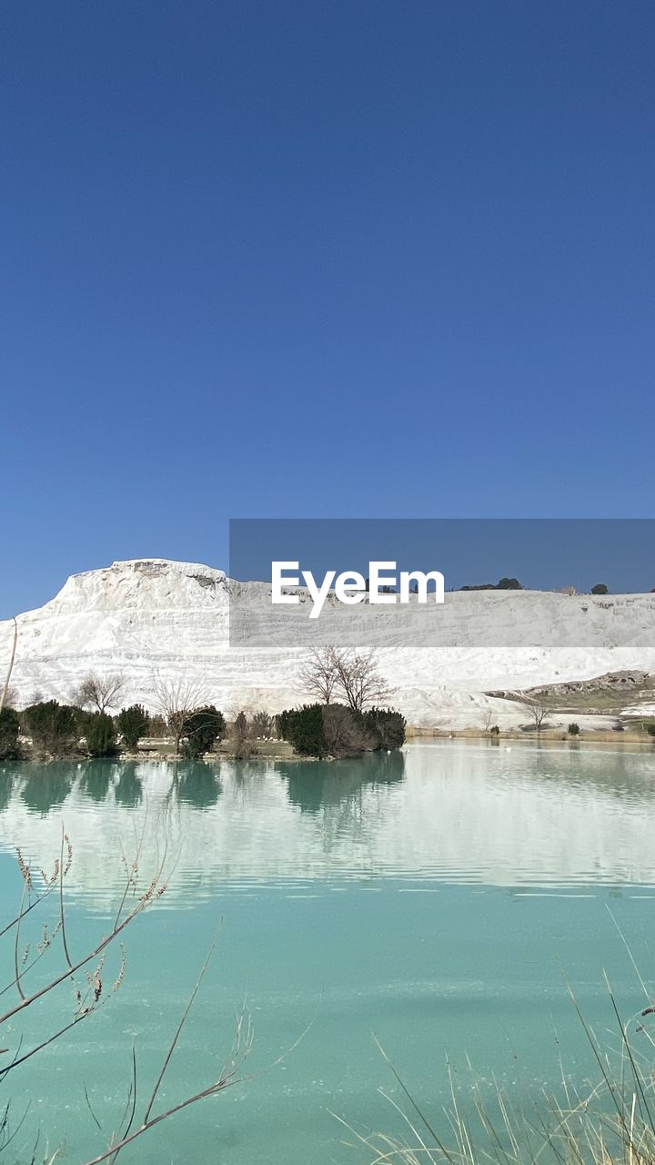 Scenic view of lake against clear blue sky