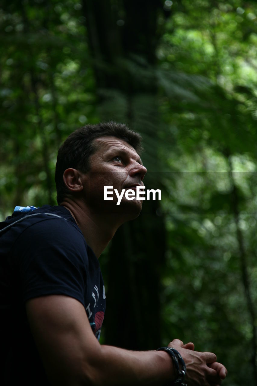 Side view of mid adult man looking up in forest