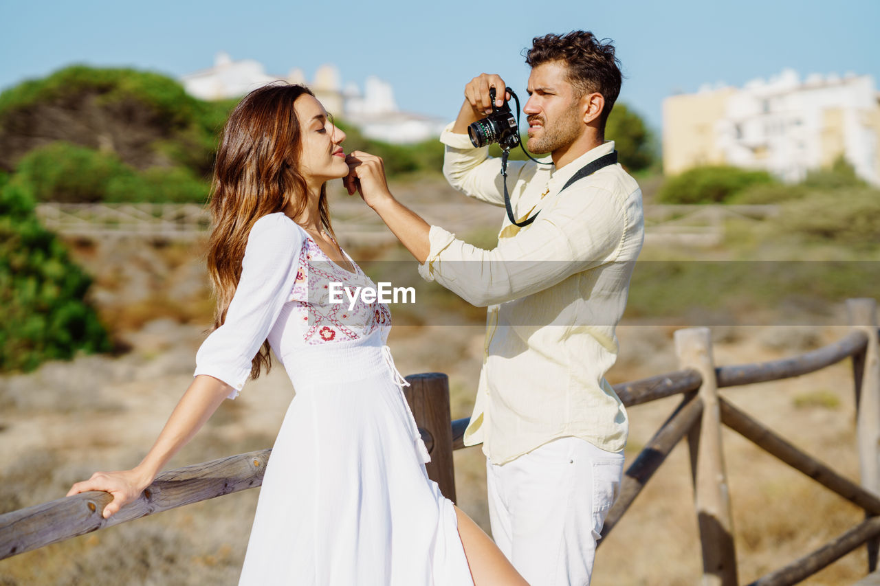 Man photographing woman standing on land