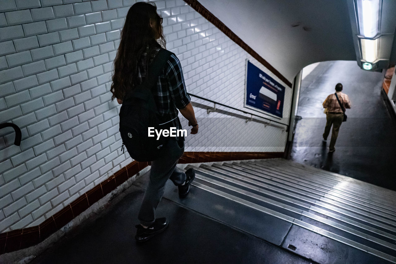 REAR VIEW OF WOMEN WALKING IN SUBWAY STATION