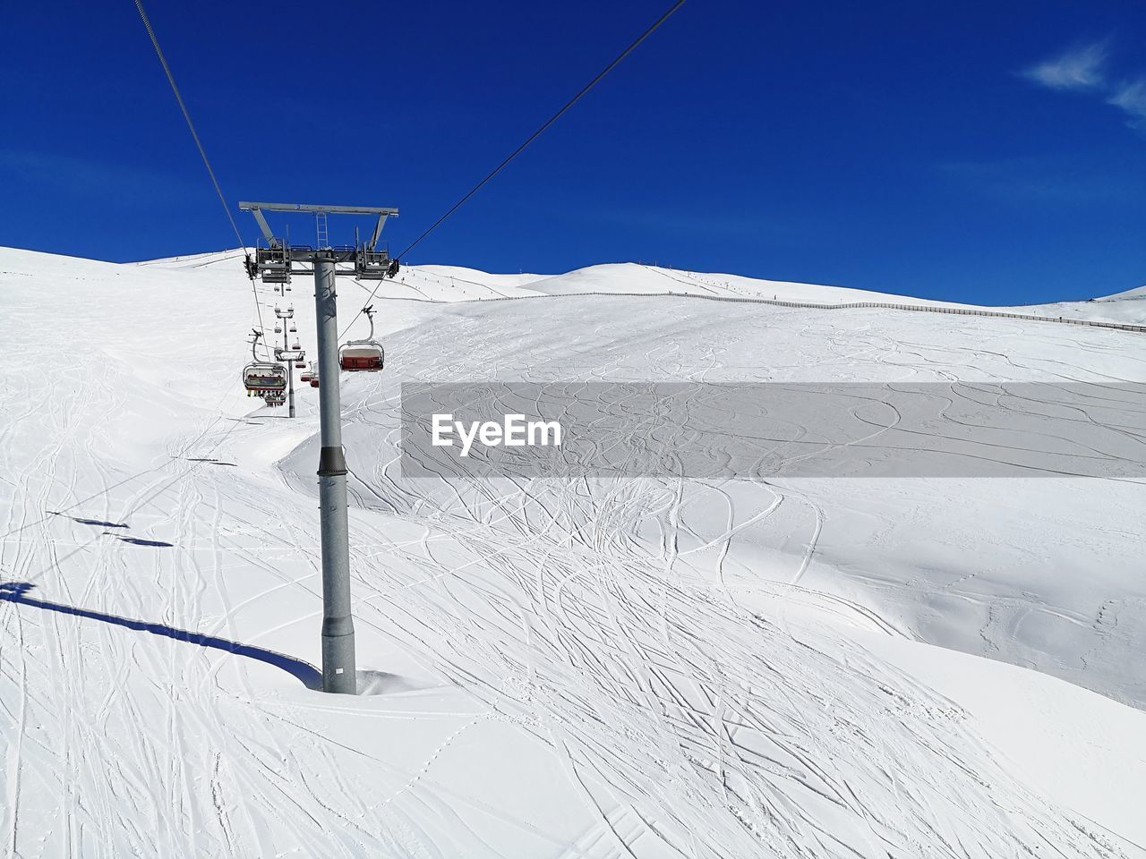 snow, piste, winter, cold temperature, skiing, mountain, landscape, ski lift, environment, ski equipment, nature, sky, scenics - nature, ski, cable, cable car, beauty in nature, white, blue, ski mountaineering, day, travel, mountain range, electricity, transportation, winter sports, non-urban scene, technology, ski touring, land, sports, ski track, sports equipment, downhill, outdoors, sunlight, overhead cable car, tranquility, vacation, tranquil scene, clear sky, nordic skiing, travel destinations, snowcapped mountain, pole, remote, holiday, communication, trip, sunny, sign