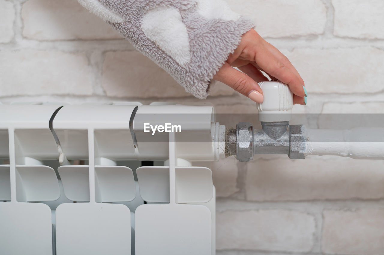 Close-up of hand holding white tap in bathroom