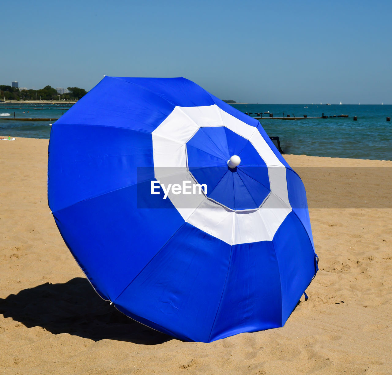 Blue umbrella on beach against clear sky