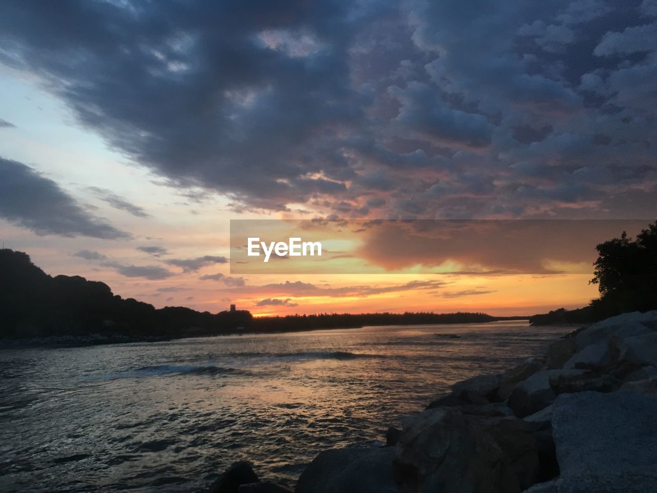 Scenic view of calm lake against cloudy sky during sunset