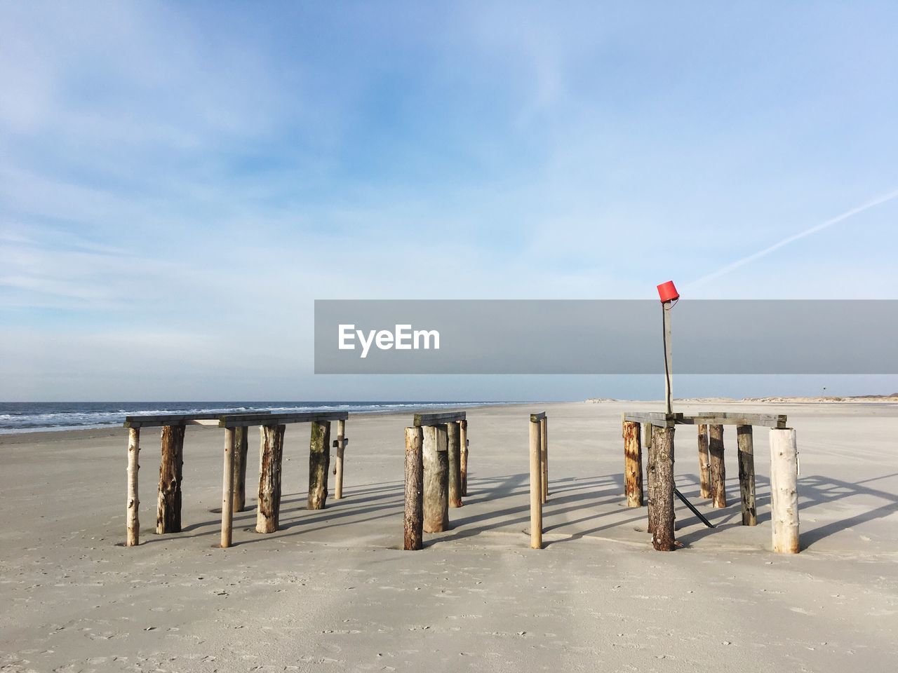 Wooden posts on beach against sky