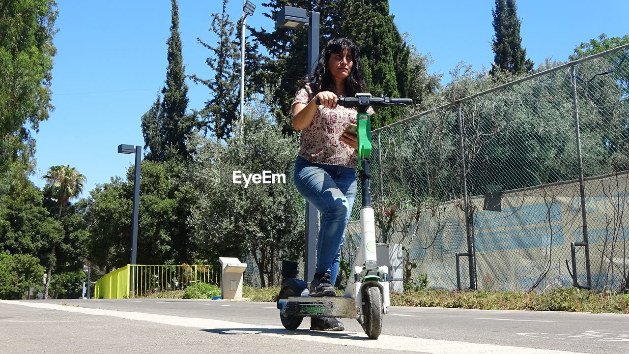 Woman riding kick scooter on road