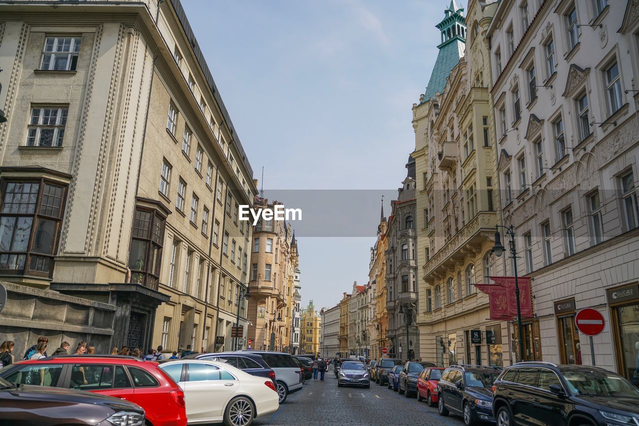 VEHICLES ON ROAD AMIDST BUILDINGS IN CITY