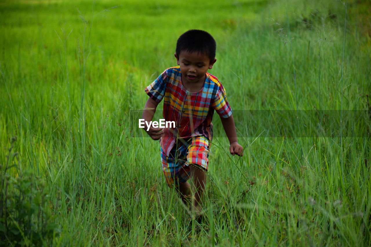 FULL LENGTH OF A BOY PLAYING ON FIELD