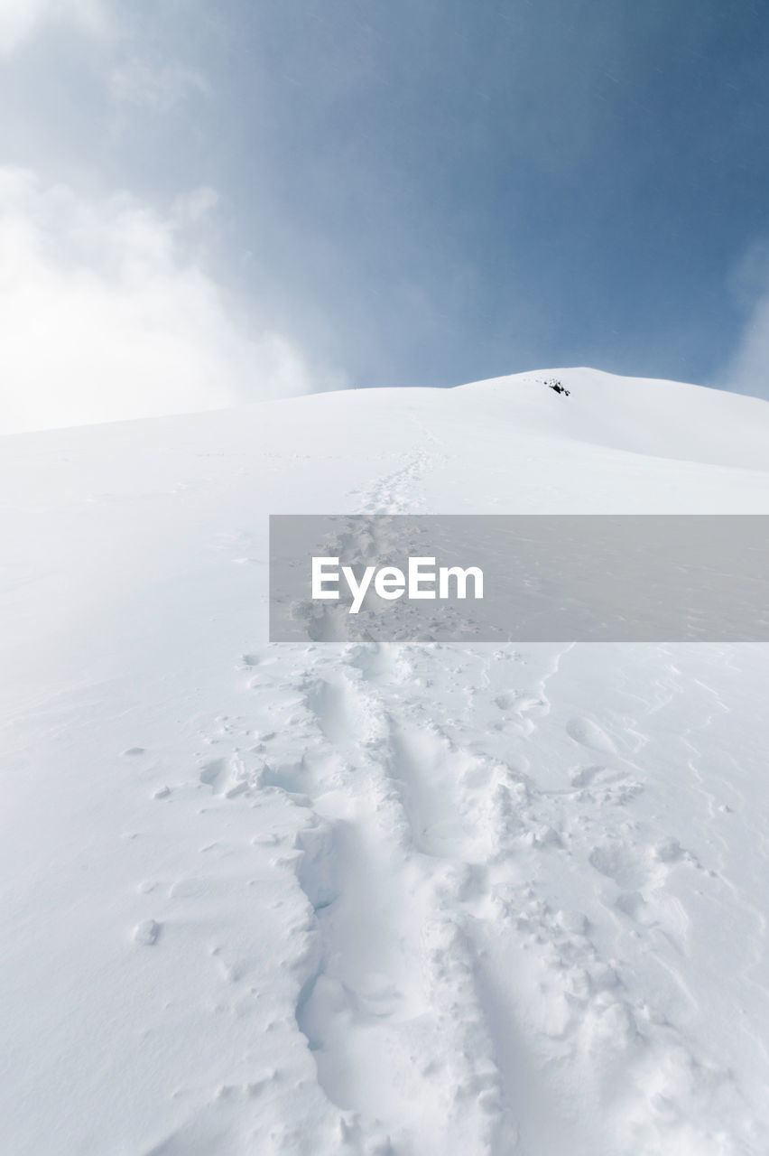 Landscape of snowy mountains with footprint on the snow during daytime in cloudy weather