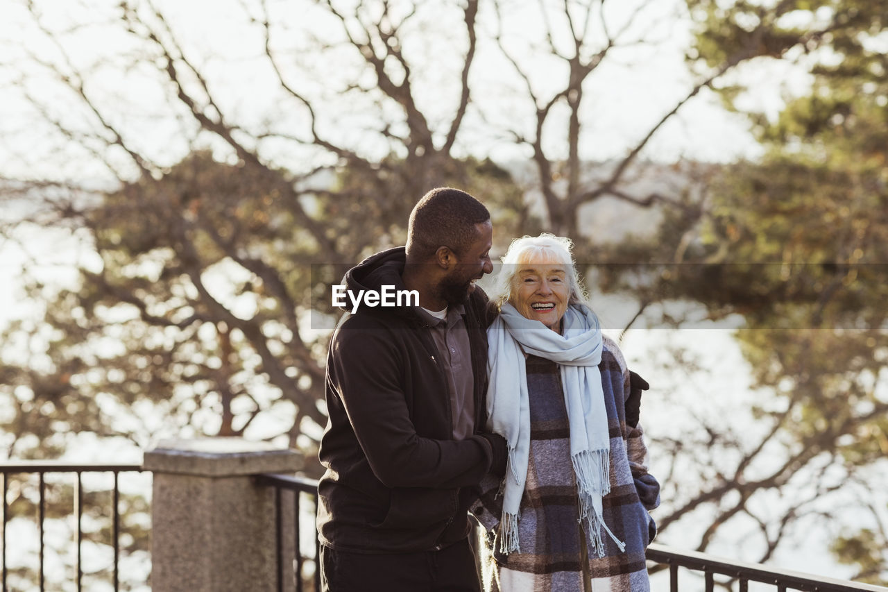 Happy male caregiver and senior woman standing in park