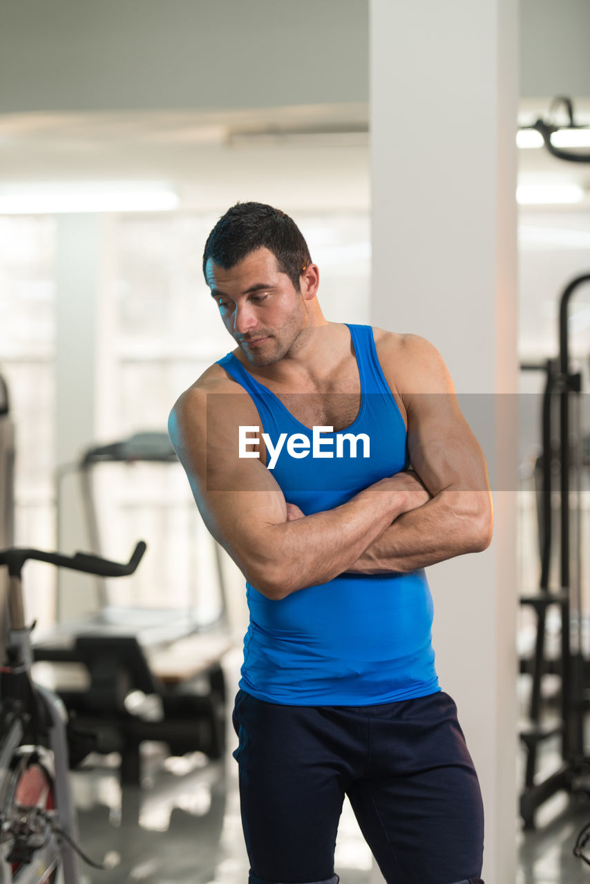 Muscular man wearing vest standing in gym