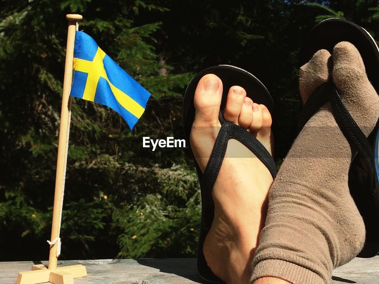 LOW SECTION OF WOMAN STANDING AGAINST FLAG ON MOUNTAIN