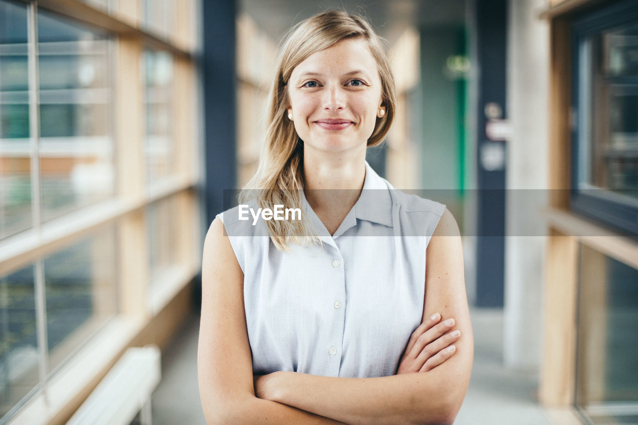 Portrait of confident woman with arms crossed standing in lobby