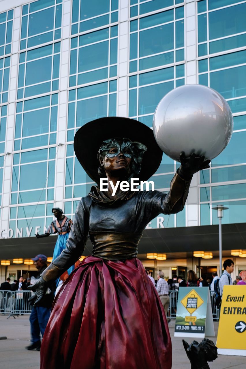 STATUE OF MAN WITH BALLOONS AGAINST SKY