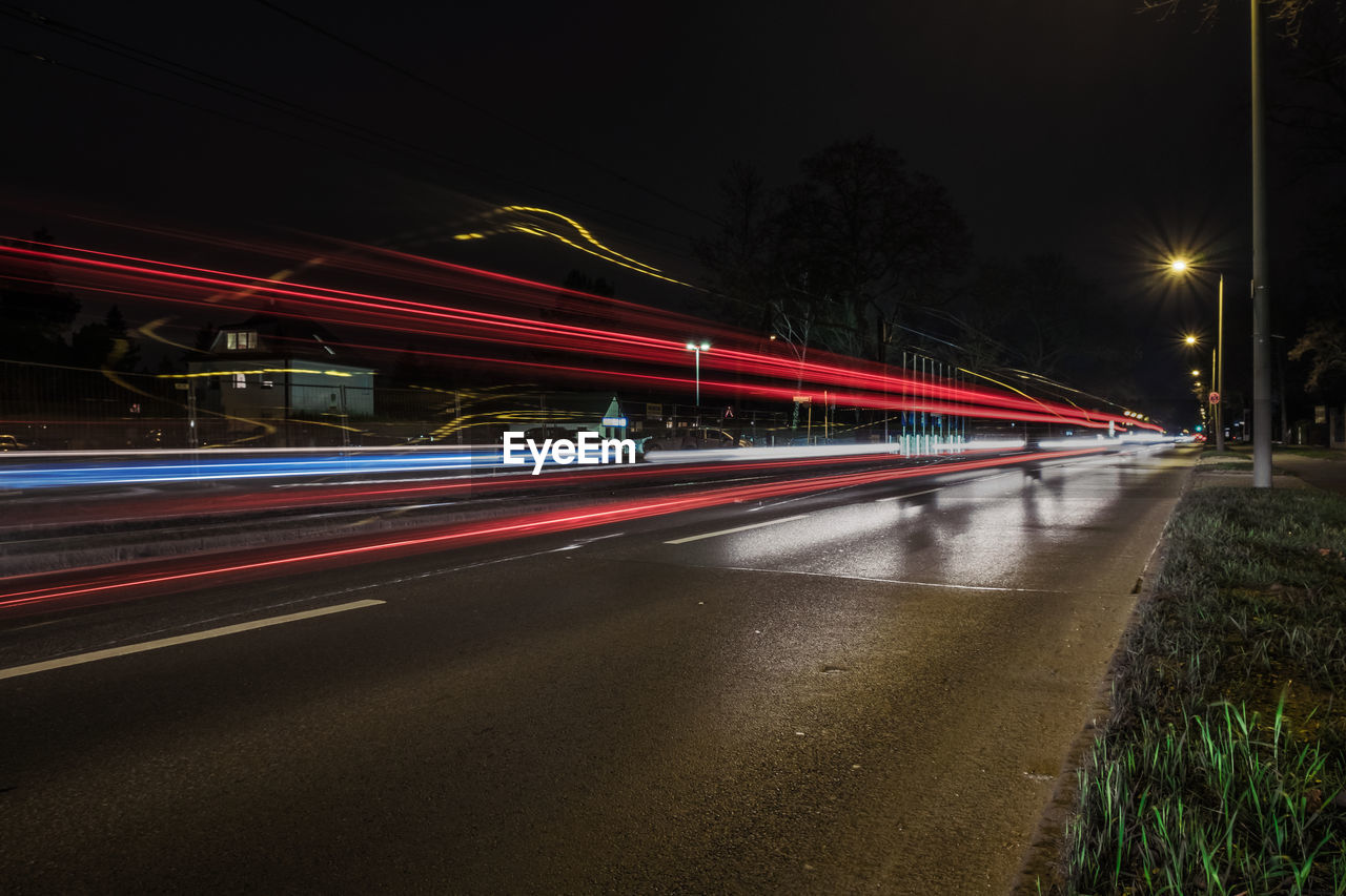 Light trails on street against sky at night