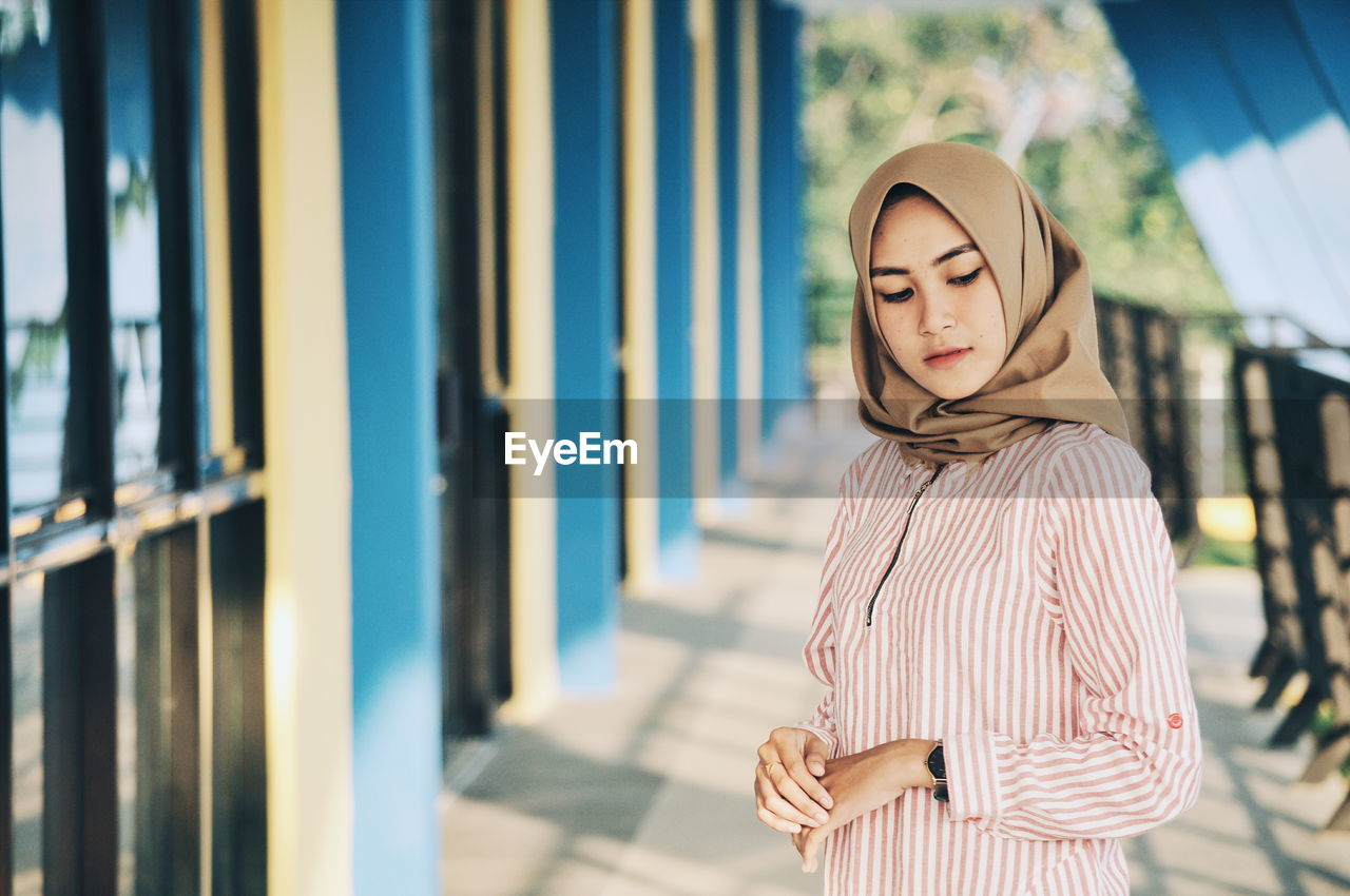 Woman wearing hijab while standing on corridor