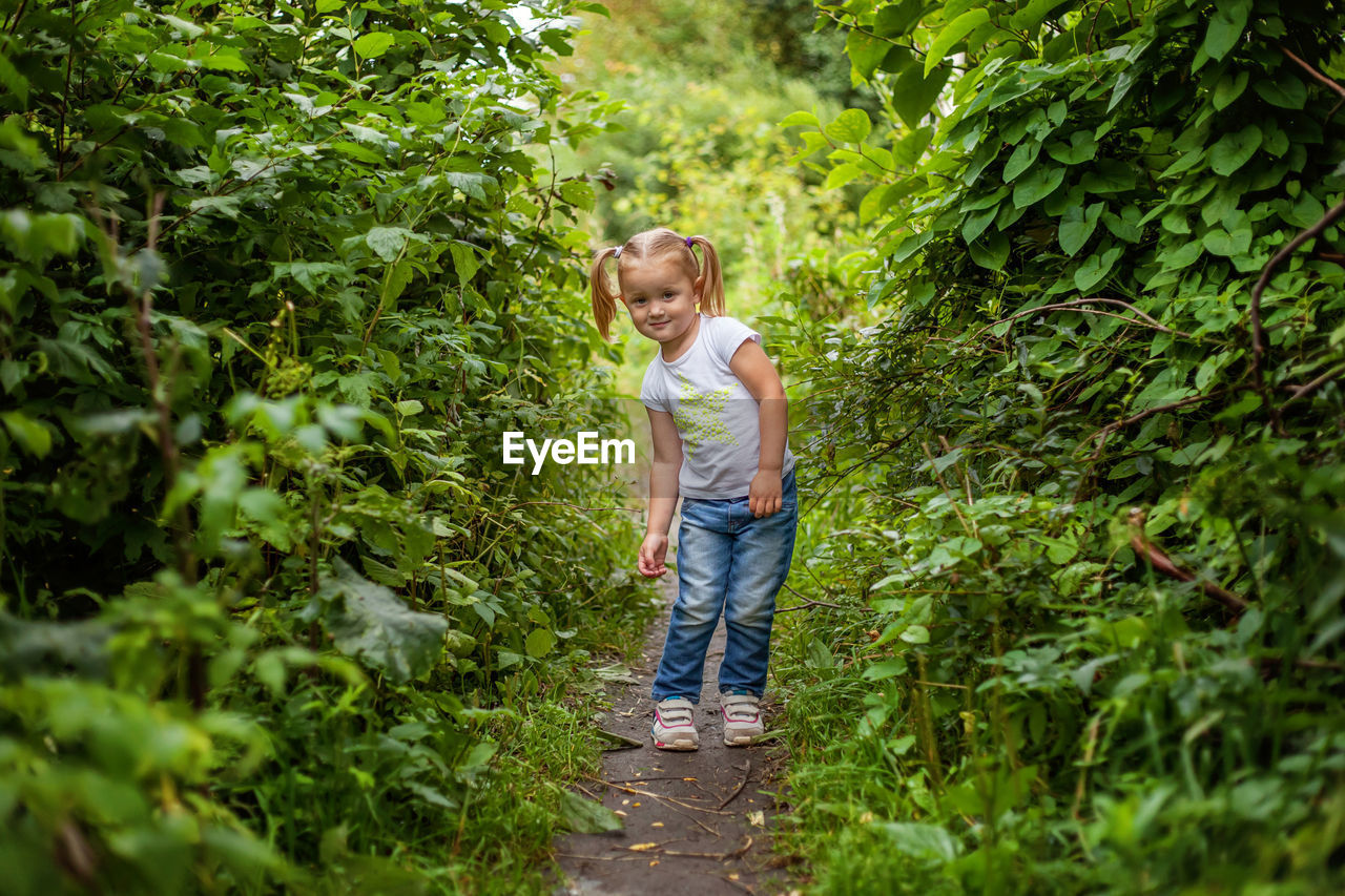 portrait of young woman standing amidst plants