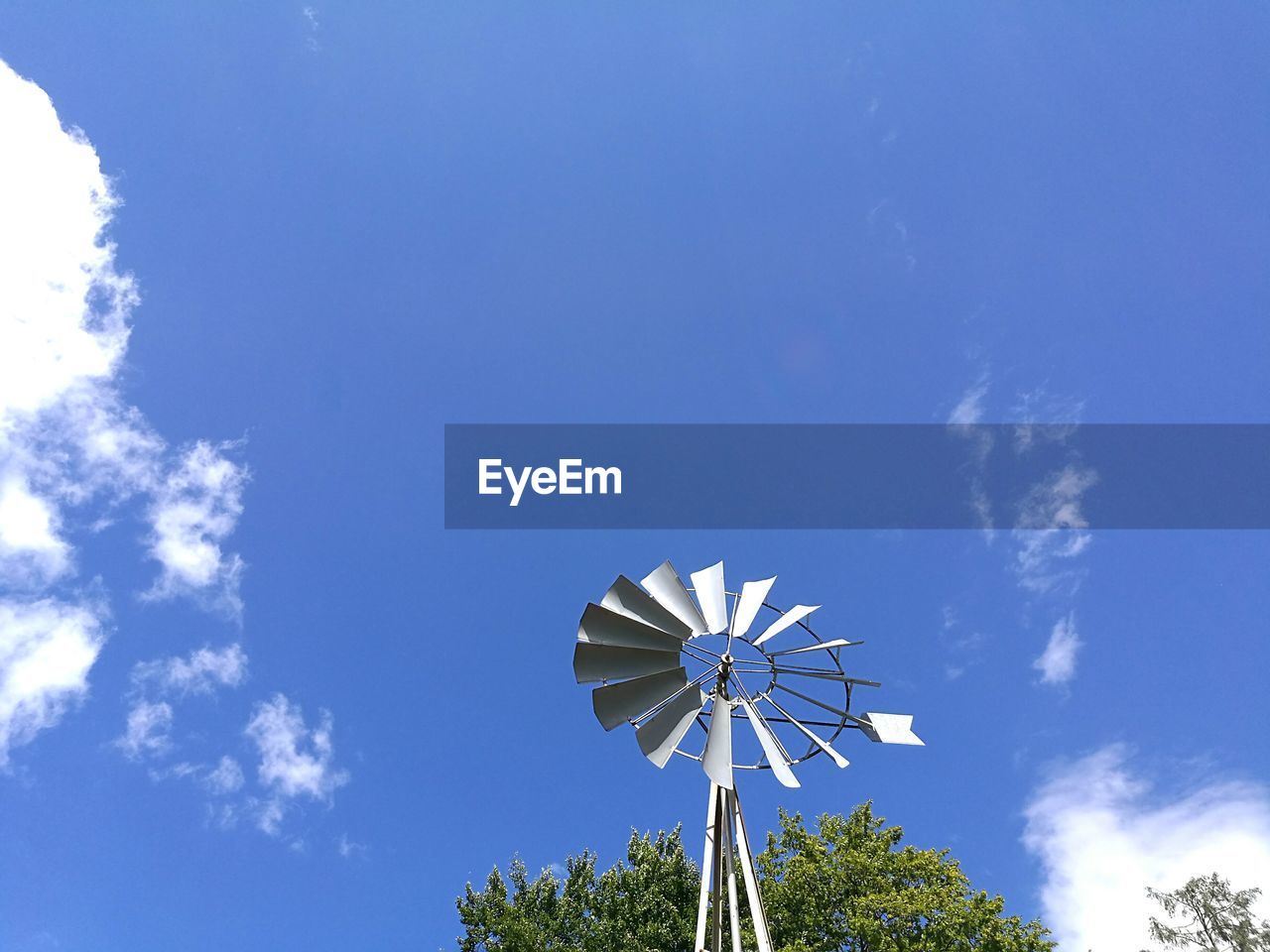 Low angle view of american-style windmill against blue sky