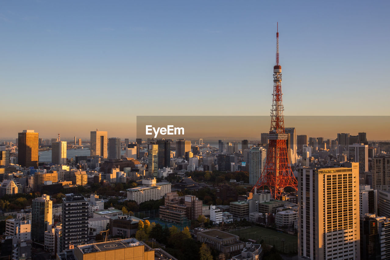 Tokyo tower and buildings in city against clear sky during sunset
