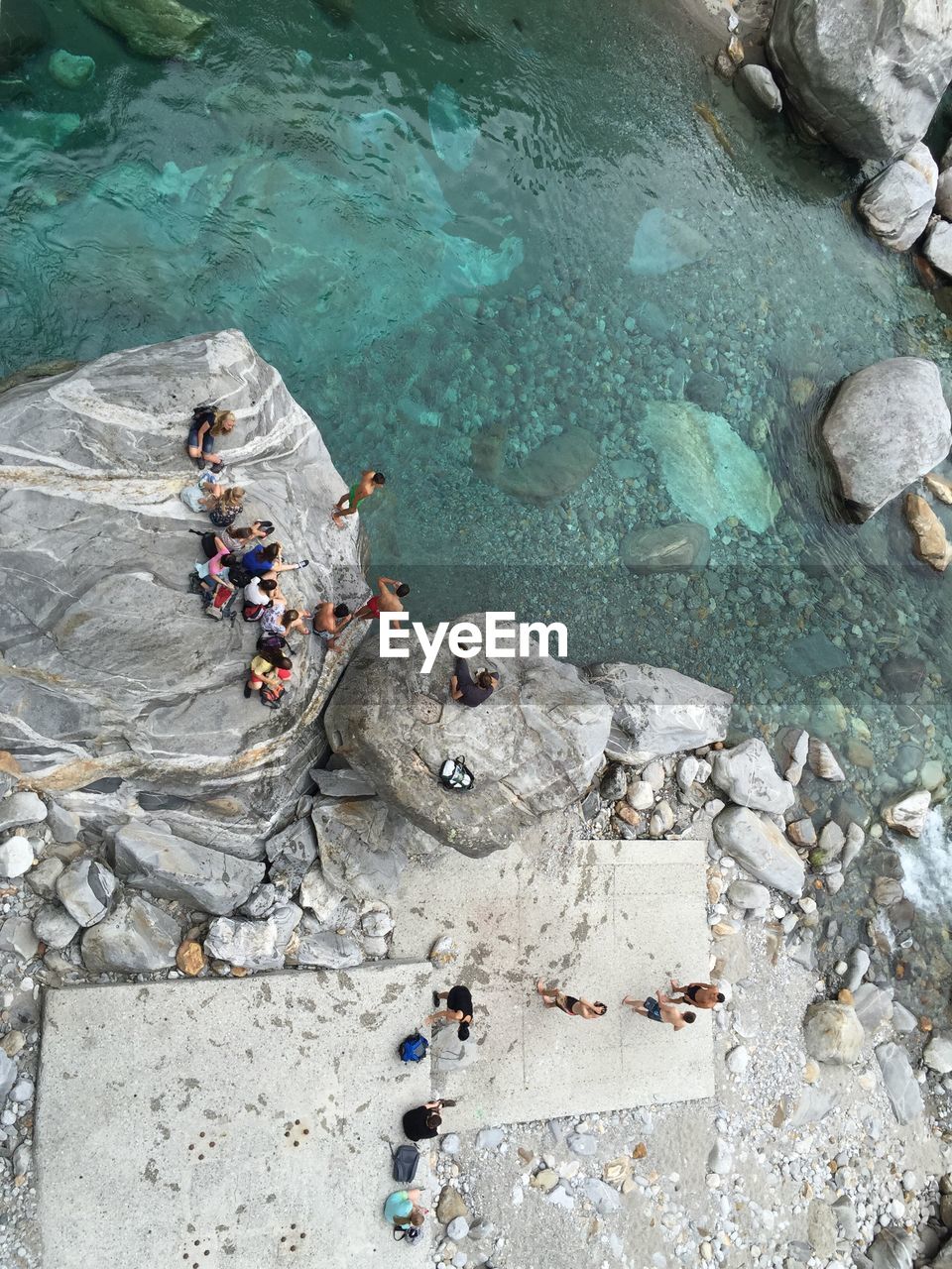 High angle view of people on rock by lake