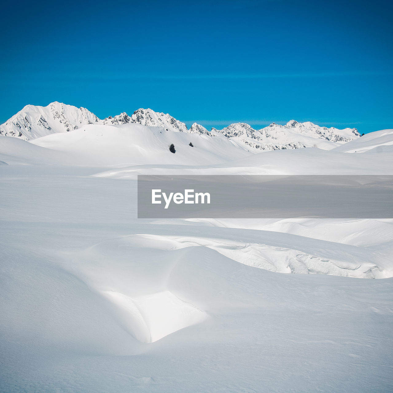 Scenic view of snowcapped mountains against blue sky