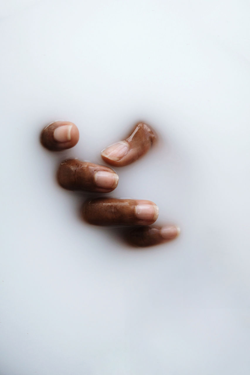 Dark skin hand in the milky smooth water substance