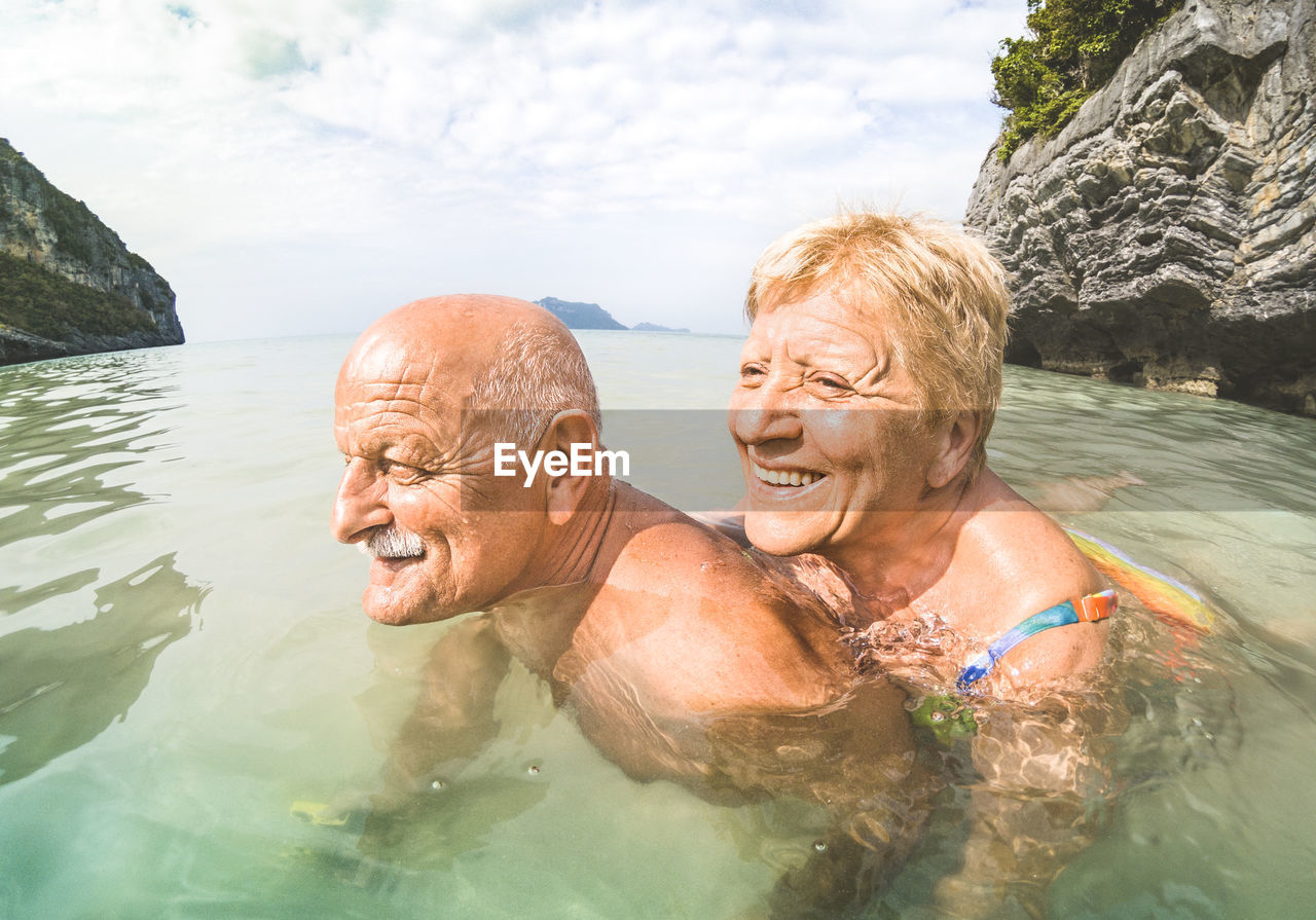 Side view of senior couple swimming in sea