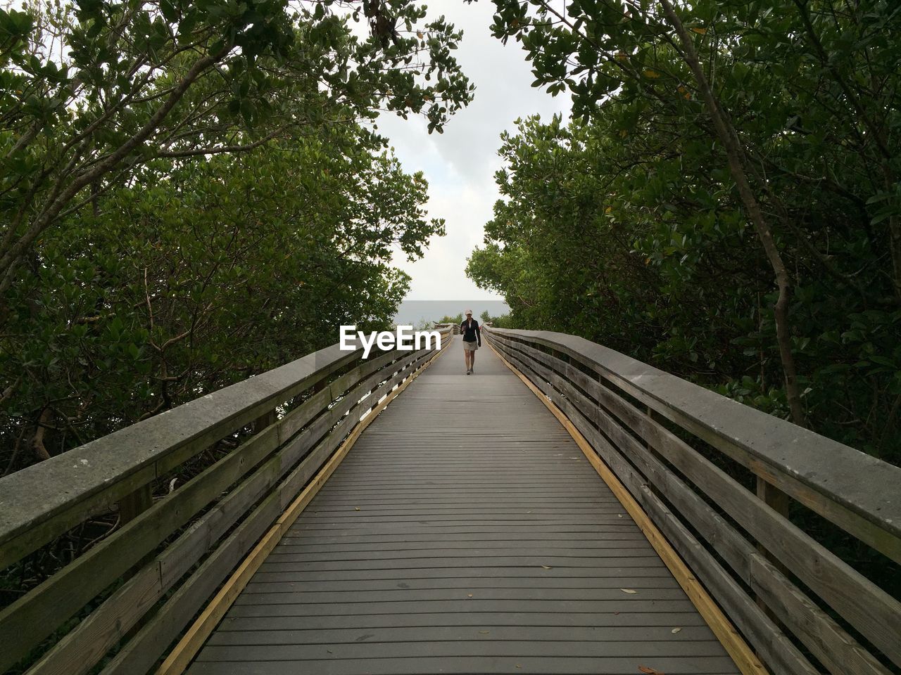 WOMAN WALKING ON FOOTBRIDGE